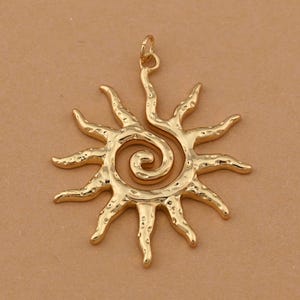 Può includere: Ciondolo a forma di sole color oro con centro a spirale e raggi strutturati. Il ciondolo ha un anello nella parte superiore per il fissaggio a una catena. Il design del sole è un simbolo popolare nella gioielleria.