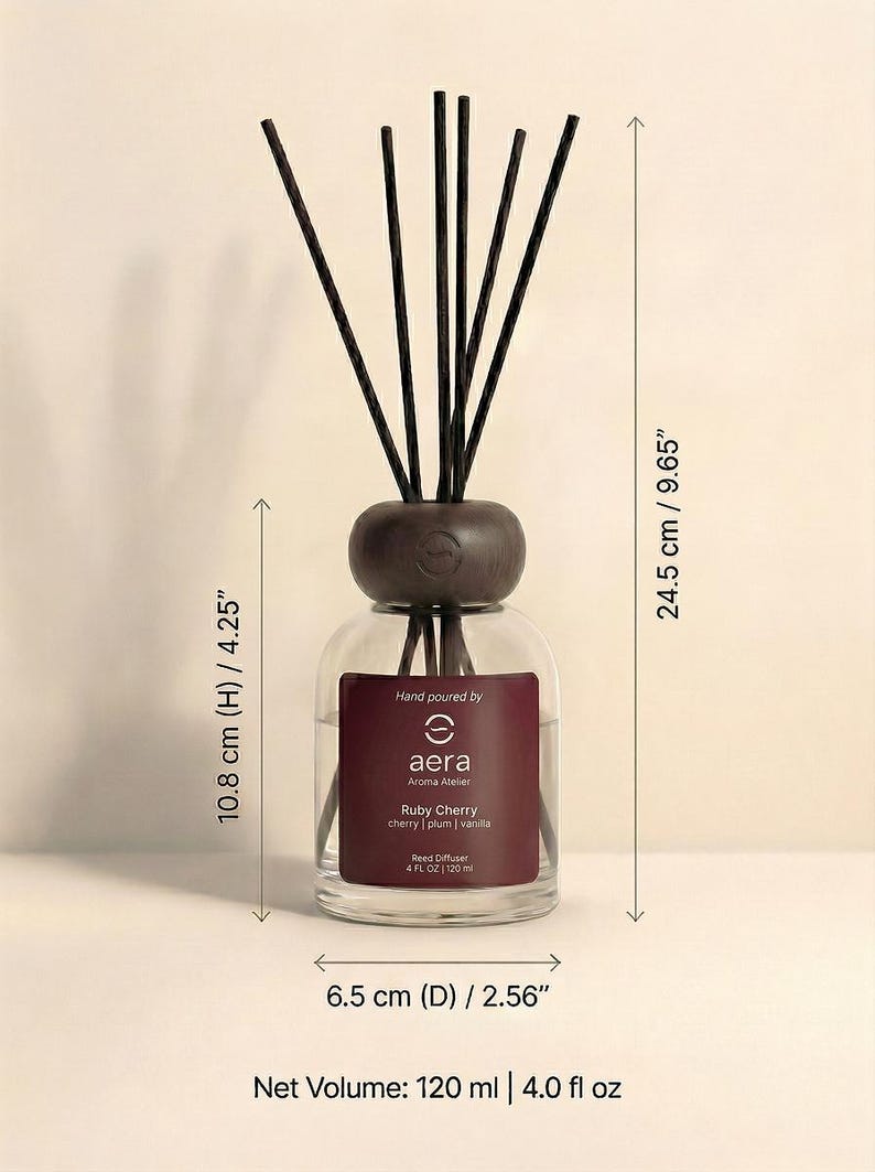 Peut inclure: Diffuseur de parfum en verre avec un dessus en bois fonc&eacute; et des b&acirc;tonnets noirs. L'&eacute;tiquette indique "Ruby Cherry" avec des notes de cerise, de prune et de vanille. Hauteur 10,8 cm, diam&egrave;tre 6,5 cm, hauteur totale 24,5 cm.