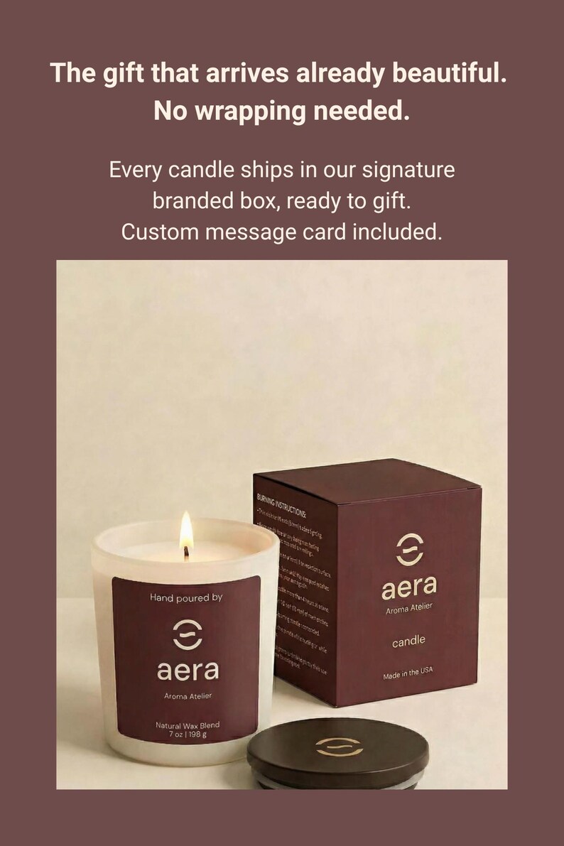 May include: A white frosted glass candle with a lit wick and a dark brown label reading Aera Aroma Atelier, 7 oz (198 g). Beside it sits a dark brown box with the Aera logo and a matching dark brown lid. Text above reads: The gift that arrives already beautiful. No wrapping needed. Every candle ships in our signature branded box, ready to gift. Custom message card included.