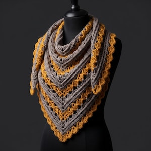 May include: A triangular crochet shawl featuring alternating rows of textured grey and mustard yellow yarn. The design incorporates a repeating openwork stitch pattern throughout the body, finished with a scalloped mustard yellow border edge.