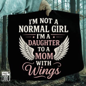 May include: Black t-shirt with white and pink text that reads "I'M NOT A NORMAL GIRL I'M A DAUGHTER TO A MOM WITH Wings". The design includes a pair of white angel wings. The shirt is held up by a person.