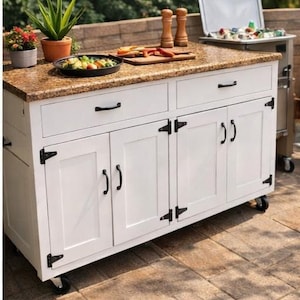 Könnte beinhalten: Weißer mobiler Outdoor-Schrank mit Granit-Arbeitsplatte, schwarzer Hardware und Rädern. Der Schrank hat zwei Schubladen und vier Türen. Das Bild enthält den Text "Mobile Outdoor Cabinet" und "Handmade in the USA."