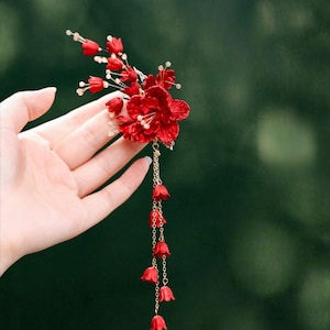 Op de afbeelding: Een levendig rood bloemen haaraccessoire met een cascade van kleine rode klokvormige bloemen. Het accessoire heeft een cluster van grotere rode bloemen en delicate witte kralen. De tekst "C01" staat in de rechterbovenhoek.
