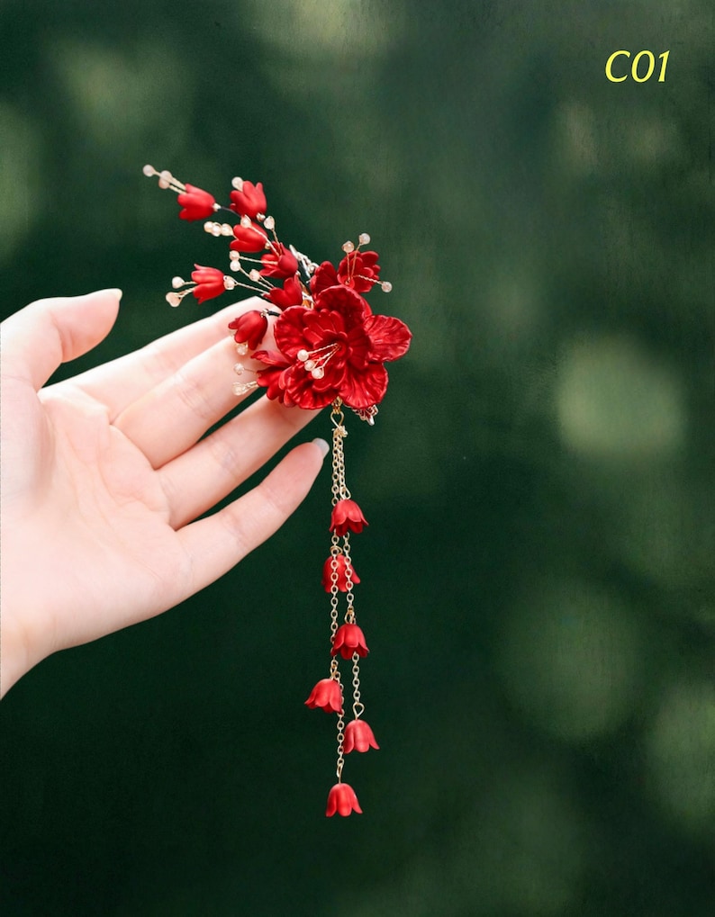 Op de afbeelding: Een levendig rood bloemen haaraccessoire met een cascade van kleine rode klokvormige bloemen. Het accessoire heeft een cluster van grotere rode bloemen en delicate witte kralen. De tekst "C01" staat in de rechterbovenhoek.