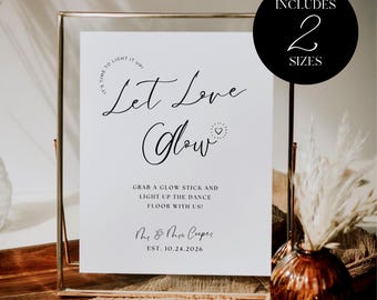 May include: A framed white sign with the text "Let Love Glow" in elegant script. The sign includes the phrase "Grab a glow stick and light up the dance floor with us!" and the names "Mr. & Mrs. Cooper" with the date "EST. 10.24.2026". A black circle indicates the sign includes two sizes.