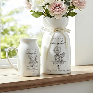 May include: A white ceramic mug and a matching white ceramic vase with a scalloped rim, both featuring black floral line art, the text "THE NEXT chapter," and the names "RACHEL" and "SOPHIA." The vase is tied with a cream ribbon and holds flowers.