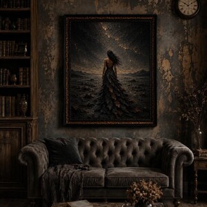 May include: A framed wall art print depicting a figure in a long, dark, textured gown standing in a desolate, rocky landscape under a stormy, cracked sky with golden light, displayed in a room with a tufted sofa and a wooden bookshelf.