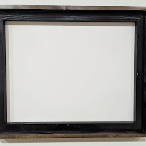 May include: Rectangular wooden picture frame with a black interior and a dark brown exterior. The frame has a simple, classic design, suitable for displaying photos or artwork. The frame is empty.