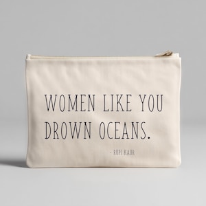 Peut inclure: Une pochette zippée de couleur crème avec l'inscription "WOMEN LIKE YOU DROWN OCEANS." et le nom de l'auteur, Rupi Kaur, imprimés en noir. La pochette présente un design simple et minimaliste.