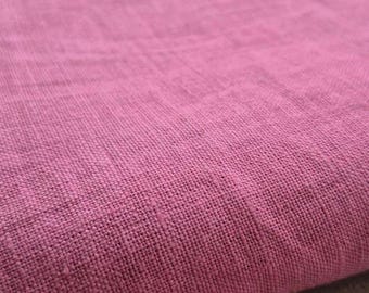 May include: Close-up of a textured, pink fabric. The material appears to be woven, with visible threads and a slightly uneven surface. The color is a vibrant, medium pink, with subtle variations in tone across the fabric.