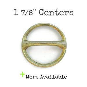 May include: A circular metal buckle with a horizontal bar across the center. The buckle is gold and silver in color. The text "1 7/8" Centers" is printed above the buckle, and "More Available" is printed below.