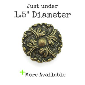 May include: Ornate, antique brass-colored button with a floral design. The button is just under 1.5 inches in diameter. Text on the image reads "Just under 1.5" Diameter" and "More Available".
