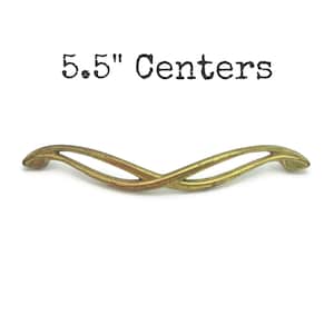 May include: A vintage-style brass cabinet pull with a curved, intertwined design. The text "5.5" Centers" is printed above the pull. The pull measures 14 cm in length.