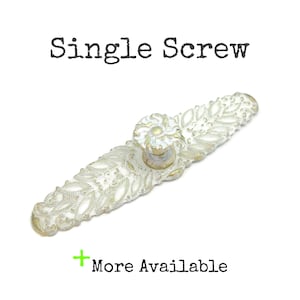 May include: A white and gold single screw cabinet pull with a floral design. The text "Single Screw" is above the pull, and "More Available" is below.