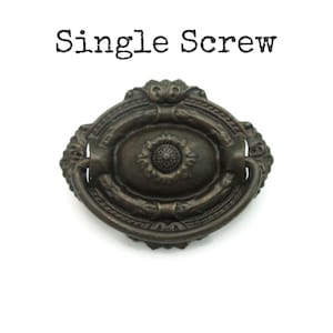 May include: An antique bronze-colored drawer pull with an oval center and decorative floral accents. The pull has a curved handle and the text "Single Screw" is above the pull.