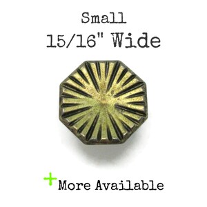 May include: A small, octagonal brass-toned button with a sunburst pattern of radiating lines. The text above reads Small 15/16" Wide, and the text below includes a green plus sign followed by the words More Available.