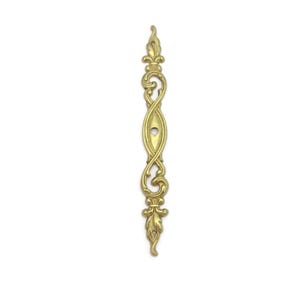 May include: A gold-colored, ornate cabinet pull with a symmetrical design. The pull features a central oval shape with a keyhole, flanked by swirling, decorative elements and topped with a fleur-de-lis. The overall length is approximately 6 inches.
