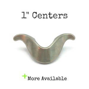 May include: A silver-toned cabinet pull with a curved design. The text "1" Centers" is above the pull, and "More Available" is below. The pull measures 1 inch in length.