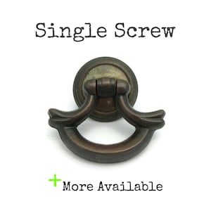 May include: A single antique bronze cabinet pull with a ring handle and a round base. The pull is attached to a white background with the text "Single Screw" and "More Available" below the pull.