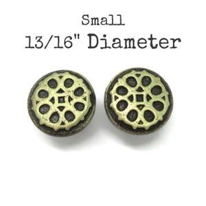 May include: Two small round buttons with a dark bronze finish and a raised, lighter gold-toned floral or gear-like pattern on the face. The text above the buttons reads Small 13/16" Diameter, indicating the size of these circular fasteners.