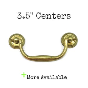 May include: A brass-toned metal drawer pull with a curved handle and two circular mounting plates. The text 3.5" Centers is printed above the hardware, and the text + More Available is printed below the hardware on a plain white background.