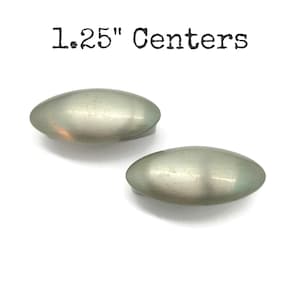 May include: Two oval cabinet pulls with a brushed metal finish. The pulls are approximately 3.18 cm in length and are set against a white background. The text "1.25" Centers" is printed above the pulls.