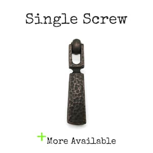 May include: A dark bronze-toned metal drop pull with a hammered texture, featuring a rounded top loop and a tapered rectangular body. The text "Single Screw" appears above the hardware, and the text "More Available" appears below it.