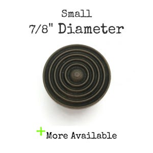 May include: A small, round, bronze-colored knob with a concentric circle design. The knob is 7/8 inch in diameter.