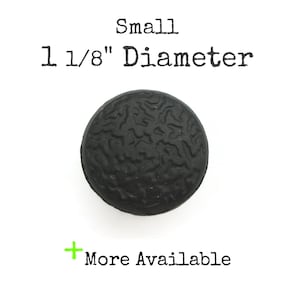 May include: A small, black, round, textured button with a diameter of 1 1/8 inches.  Small.
