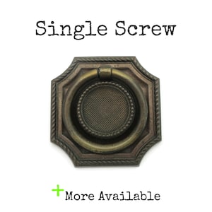 May include: An antique-style brass drawer pull with a ring handle. The pull has a square backplate with a rope-like border and a circular center with a textured pattern. The text "Single Screw" is above the pull, and "More Available" is below.