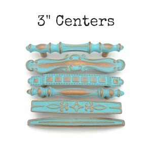 May include: A collection of six decorative cabinet pulls with a distressed turquoise and bronze finish. The text "3" Centers" is at the top. Each pull has a unique design, ranging from bamboo-style to ornate patterns. The pulls are approximately 3 inches in length.