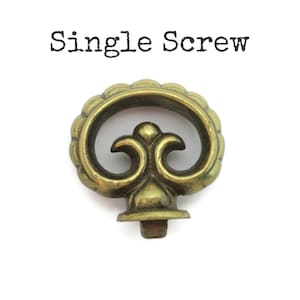 May include: A single brass screw with an ornate, floral design. The screw head features a scalloped edge and a central, stylized flourish. The text "Single Screw" is printed above the screw in black.