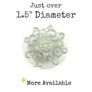 May include: White and gold decorative knob with a floral design. The knob is approximately 1.5 inches in diameter. The text "Just over 1.5" Diameter" is printed above the knob. The text "More Available" is printed below the knob.
