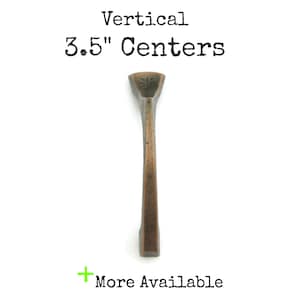 May include: A vertical, 3.5" center, bronze cabinet pull with a simple, rectangular design.