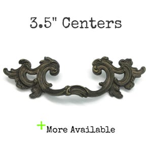 May include: Ornate bronze-toned drawer pull with a scrolling design. The pull measures 3.5 inches between the centers of the mounting holes. Text on the image reads "3.5" Centers" and "More Available".