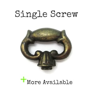 Peut inclure: Une poignée de tiroir en métal couleur laiton avec une poignée incurvée et une base décorative centrale. Le texte Single Screw est imprimé au-dessus de l'objet et le texte + More Available est imprimé en dessous sur un fond blanc.