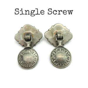 May include: Two antique silver-toned drawer pulls with a decorative floral design. Each pull has a round handle and a decorative backplate. The text "Single Screw" is above the pulls.