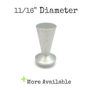 May include: A silver-colored, cone-shaped object with a rounded base. The diameter is 11/16 inches. The text "11/16" Diameter" is above the object, and "More Available" is below.