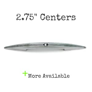 Peut inclure: Une poignée de meuble argentée avec trois lignes horizontales et la lettre "E". Le texte "2.75" Centers" est au-dessus de la poignée, et "More Available" est en dessous. Ce matériel mesure 7 cm.