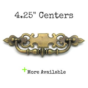 May include: Antique brass drawer pull with ornate detailing. The pull measures 4.25 inches between centers. The image also includes the text "4.25" Centers" and "More Available".