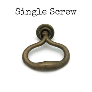 May include: A single antique brass-colored drawer pull with a circular top and a curved handle. The text "Single Screw" is printed above the drawer pull in black letters. The hardware is designed for furniture.