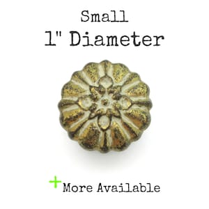 May include: A small, antique-style decorative button with a 1-inch diameter. The button has a detailed, floral design with a gold and bronze finish. The text "Small 1" Diameter" is above the button, and "More Available" is below.