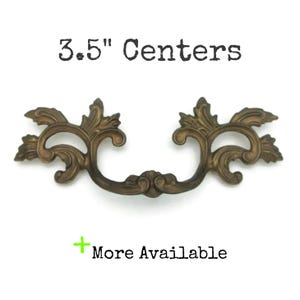 May include: Ornate bronze-colored drawer pull with a decorative floral design. The pull has a 3.5-inch center-to-center measurement. Text on the image reads "3.5" Centers" and "More Available".