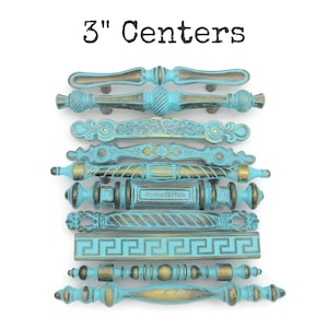 May include: A collection of ten antique-style cabinet pulls in various designs. The pulls are a distressed turquoise color with gold accents. The text "3" Centers" is at the top of the image. Each pull measures 3 inches.