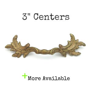 May include: A set of three ceramic mugs with a speckled, cream-colored glaze. Each mug features a different hand-painted floral design in shades of blue, green, and yellow. The mugs have a simple, rounded shape and a comfortable handle.