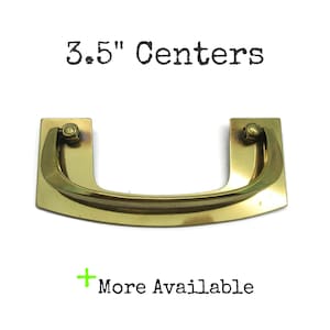 May include: A polished brass drawer pull with a curved handle and rectangular mounting plates. The text 3.5" Centers is printed above the hardware, and the text + More Available is printed below the hardware on a plain white background.