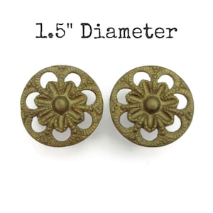 May include: Two antique brass drawer pulls with a floral design. Each pull is 3.8 cm in diameter. The pulls have a detailed, openwork pattern around the central floral motif. The text "1.5" Diameter" is above the pulls.