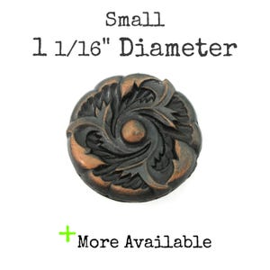 May include: A round, dark copper-toned metal button with a raised, swirling floral relief pattern. The text above reads Small 1 1/16" Diameter, and the text below reads + More Available. The button features a central circular accent.