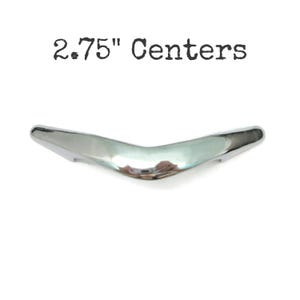 May include: A polished chrome cabinet pull with a V-shaped, arched design. The hardware features a smooth, reflective metallic surface and is labeled with the text 2.75" Centers, indicating the distance between the mounting holes.