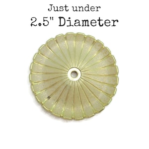 May include: A gold-colored metal ceiling fixture with a decorative, scalloped edge. It measures just under 2.5 inches in diameter.